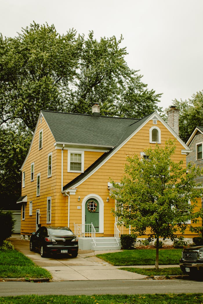 A charming yellow two-story house with a green door, car parked outside.